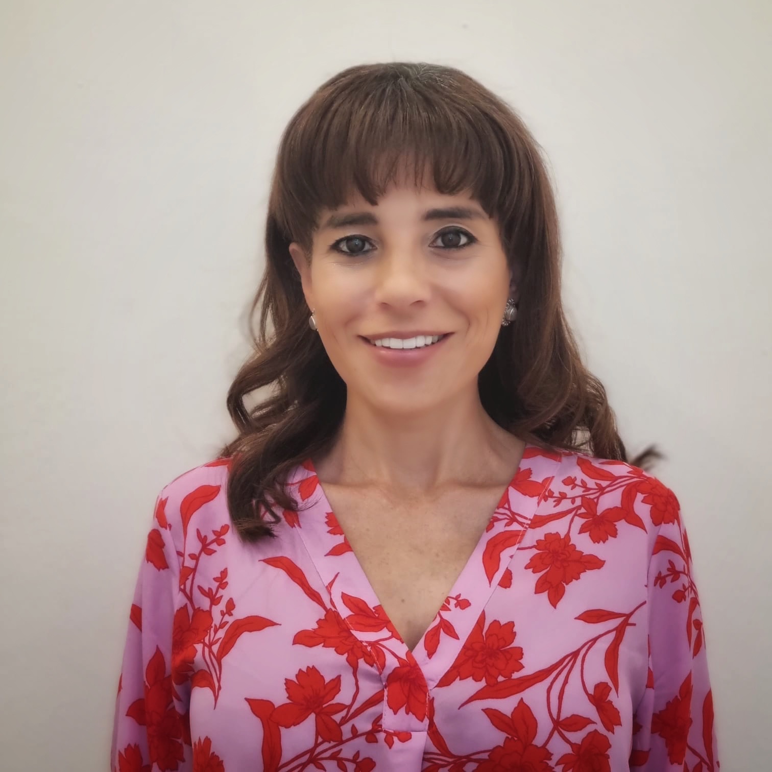 Larissa Trsitán con camisa formal rosada de flores rojas.